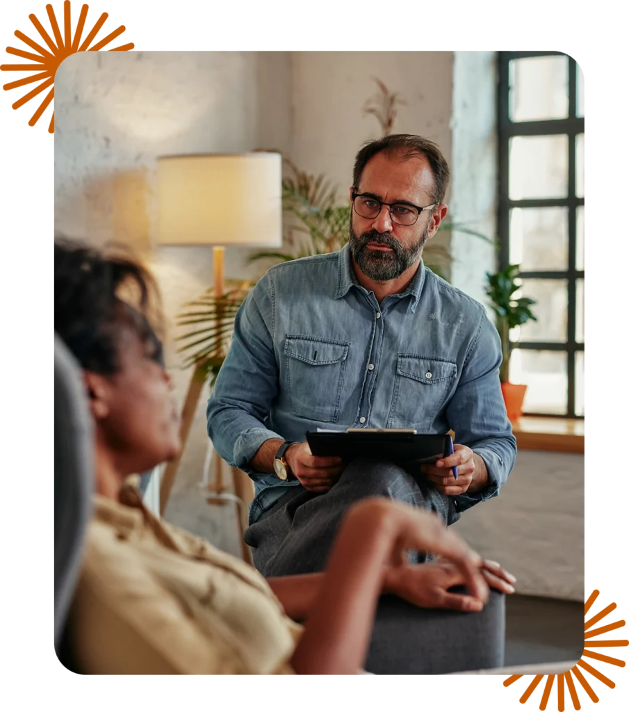 Male therapist in private practice taking notes during a session with a client